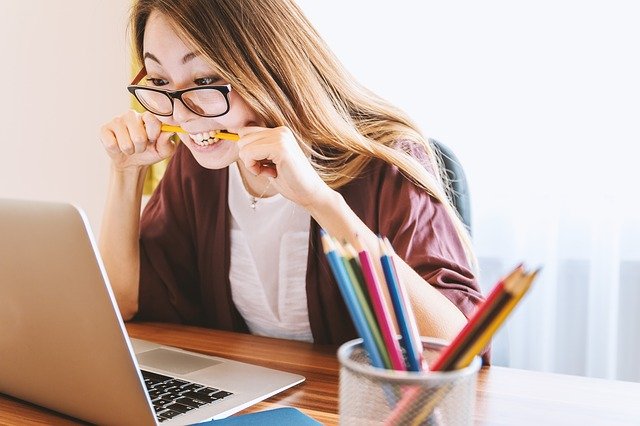 lady in front of a computer with a pencil in her mouth