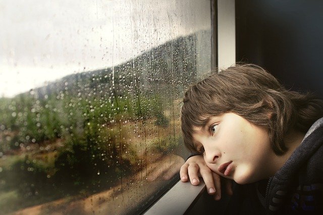 boy watching the rain through the window