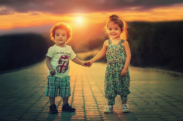 2 kids, a boy and a girl holding hands